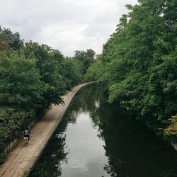 Rear view of woman cycling by canal