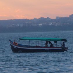 Boat sailing in sea at sunset