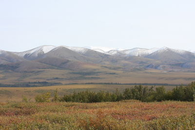 Scenic view of land and mountains against clear sky