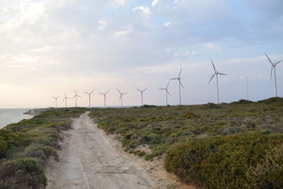 Wind turbines on land against sky