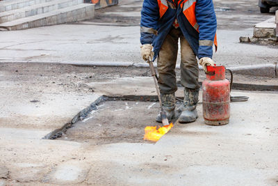 A road worker prepares a pothole in the asphalt for repair by heating the damaged asphalt pavement