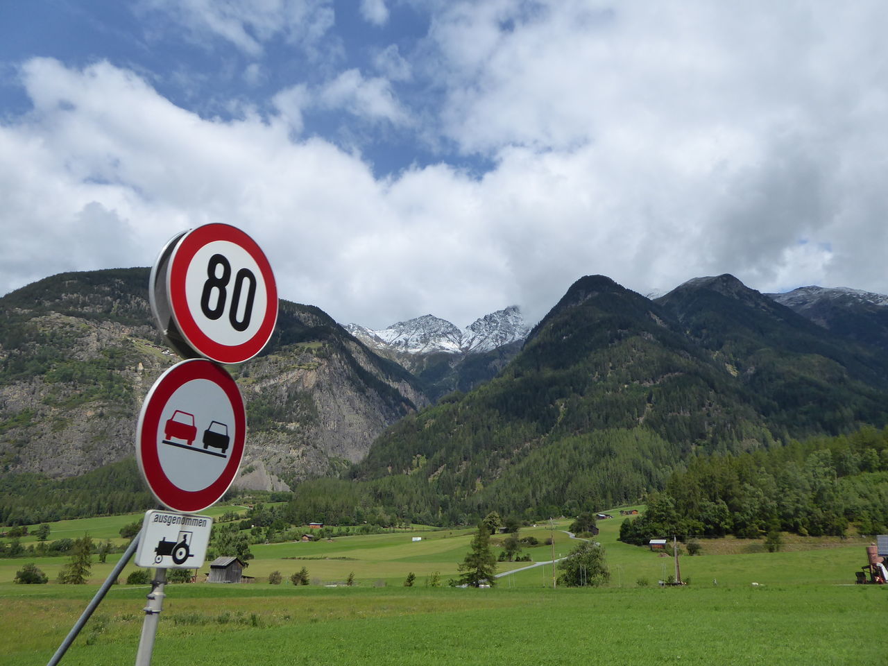 ROAD SIGN ON LANDSCAPE AGAINST MOUNTAINS