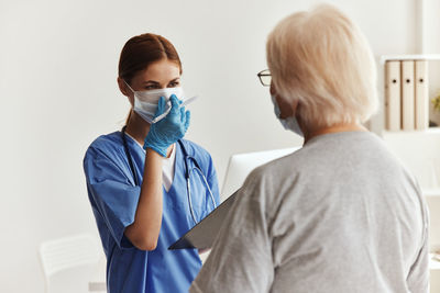 Side view of boy wearing surgical mask while standing against white background