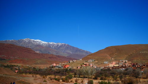 Scenic view of houses and mountains against clear blue sky