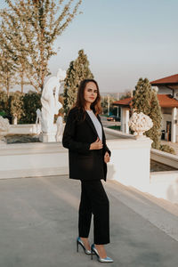 Young woman in black trouser suit and silver shoes on the background of the park