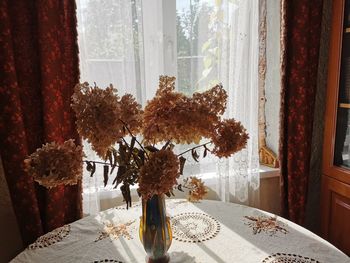 Close-up of flower vase by window at home