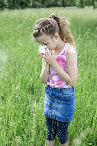 Girl sneezing while standing on field