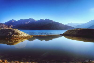 Scenic view of lake and mountains against clear blue sky