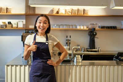 Portrait of young woman standing in kitchen