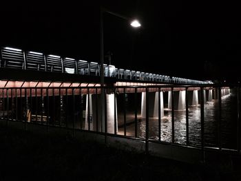 Illuminated bridge over river at night