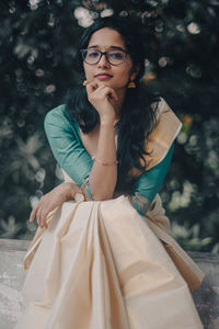 Portrait of young woman sitting near trees taken during the onam festival 