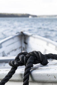 Close-up of rope tied on bollard against sea