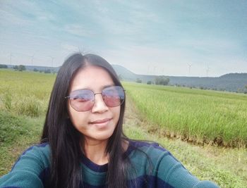 Portrait of smiling young woman wearing sunglasses on field