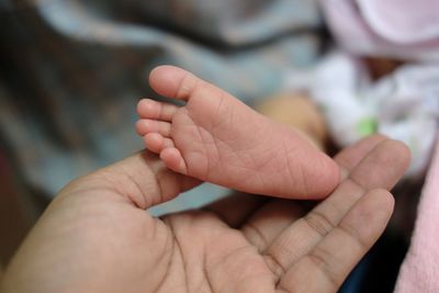 Cropped image of father holding feet of baby