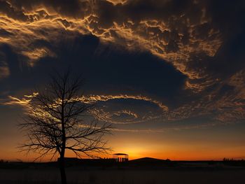 Silhouette bare tree against dramatic sky during sunset