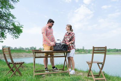 Side view of woman using laptop while sitting on field