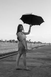 Full length portrait of woman standing on umbrella against rain