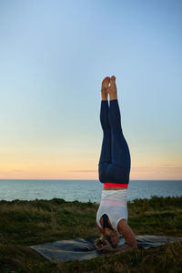 Rear view of woman standing at beach against clear sky