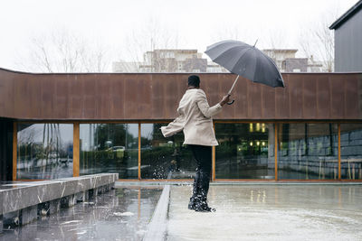 Full length of man standing on wet road during rainy season