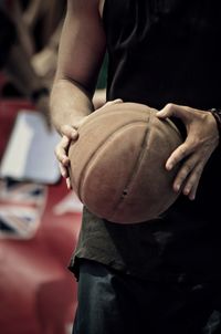 Midsection of man holding ball while standing on court