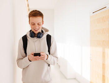 Portrait of young woman using mobile phone while sitting on bed at home