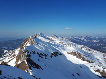 Scenic view of snowcapped mountains against clear blue sky