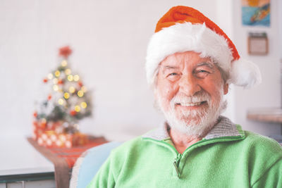 Portrait of smiling senior man wearing santa hat at home
