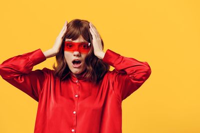 Portrait of young woman against yellow background