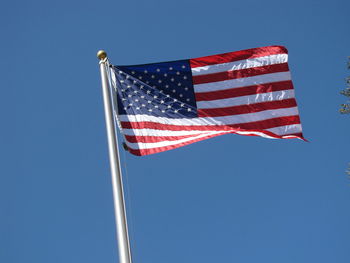 Low angle view of flags flag against clear blue sky