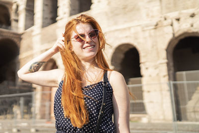 Optimistic tourist adjusting hair outside old attraction