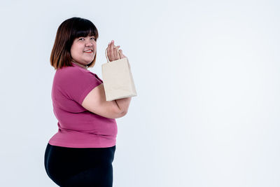 Smiling young woman standing against pink background