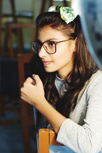 Thoughtful woman wearing eyeglasses while sitting on chair