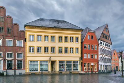 Buildings by river against sky