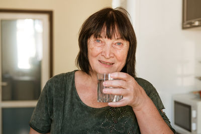 Portrait of mature man drinking glass at home