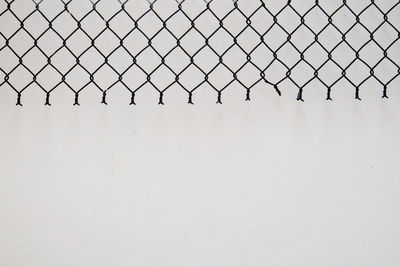 Close-up of chainlink fence against sky during winter