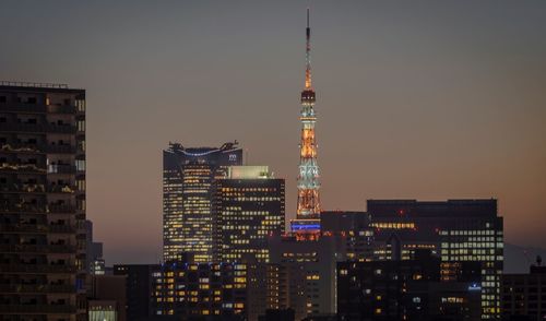 Illuminated buildings in city against sky at night