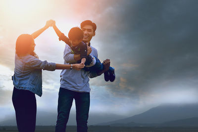Low angle view of friends standing against sky