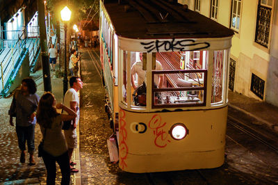 People on sidewalk by train tramp at night