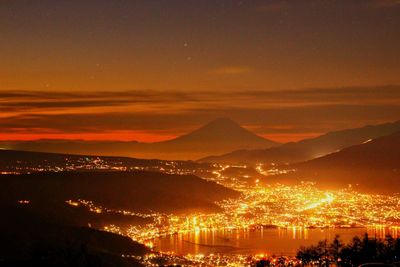 Silhouette mountains by lake against sky at night