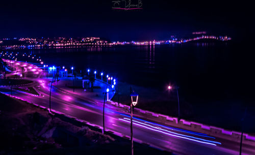 Light trails on illuminated city by river at night