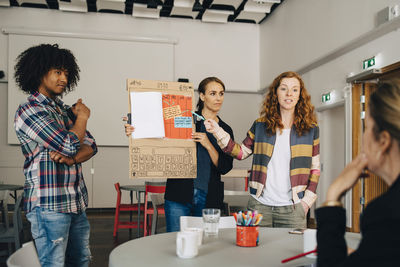 Confident businesswoman with colleagues explaining strategy to female manager at creative office