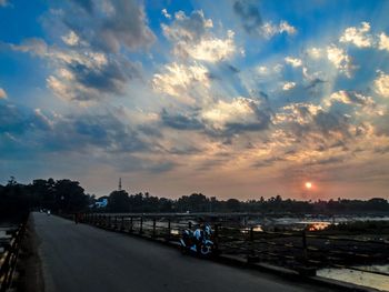 Road by sea against sky during sunset