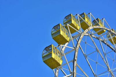 Low angle view of ferris wheel against clear blue sky