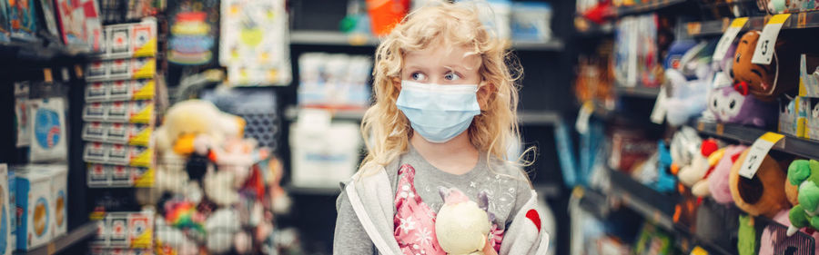 A new normal. caucasian girl child in face mask shopping in store. web banner header for website.