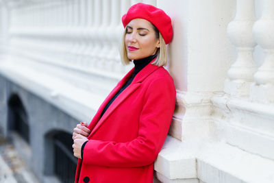 Young woman standing against wall