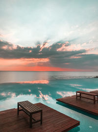 High angle view of table on wooden platform by sea against sky