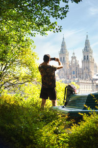 Rear view of man photographing church in city