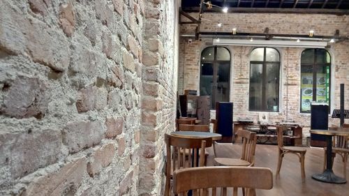 Empty chairs and table against wall in old building