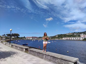 Woman standing by sea against sky