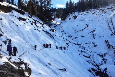 Group of people walking on snow covered mountain